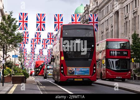 Ein Blick auf die Regent Street mit den Flaggen und der Flagge, die für das Queen`s Platinum Jubilee bereit sind, gesehen mit roten Londoner Bussen, aufgenommen am 21.. Mai 2022. Stockfoto